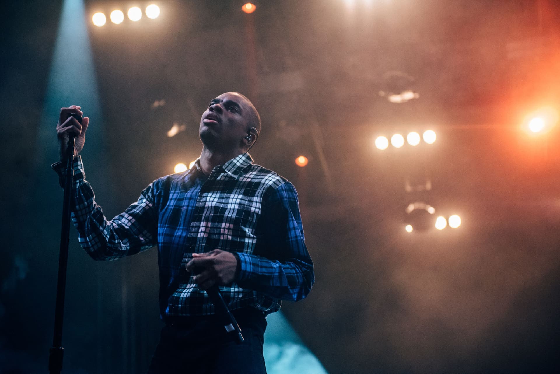 A comedian on stage holding a microphone under a spotlight